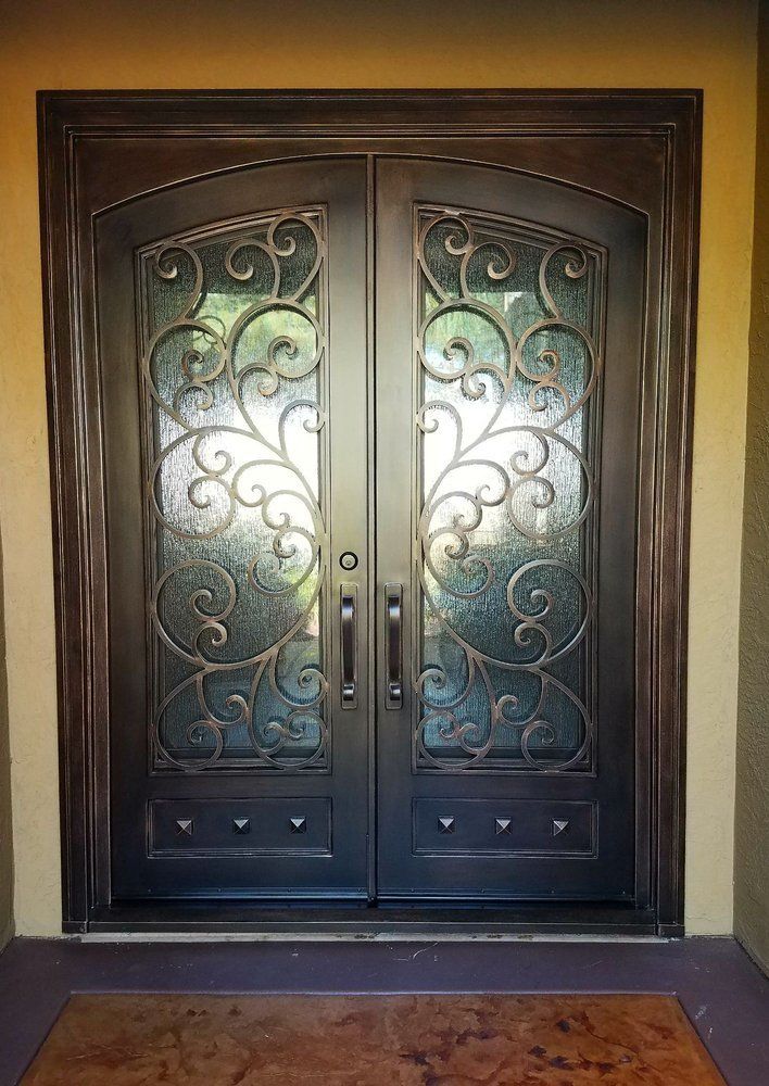 Double arched black doors with frosted glass panels and ornate iron scrollwork.