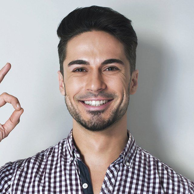 Man with dark hair and a short beard smiles and gives an